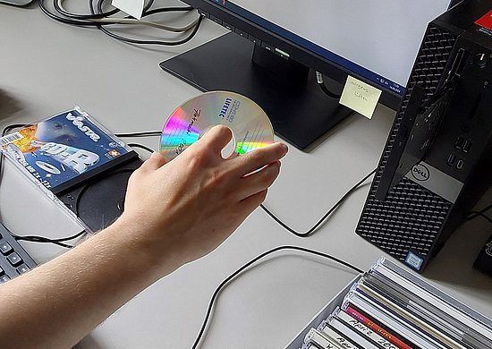 Hand, die eine CD in ein Laufwerk einführt